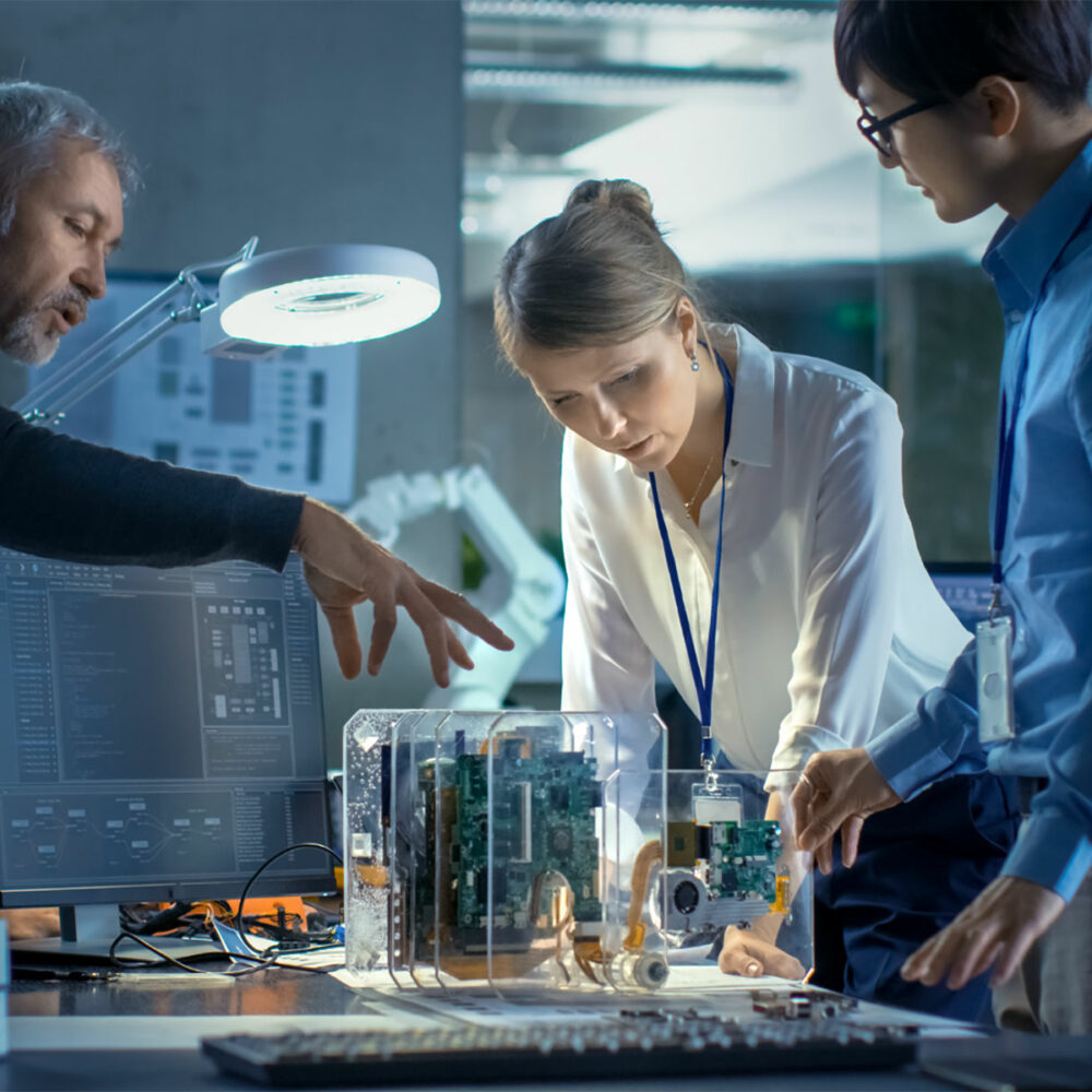 3 Leute vor Technikmodell am Tisch besprechen sich